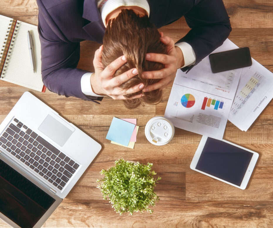51923322 - businessman in panic. a young man sits at his desk and holds his hands on his head.